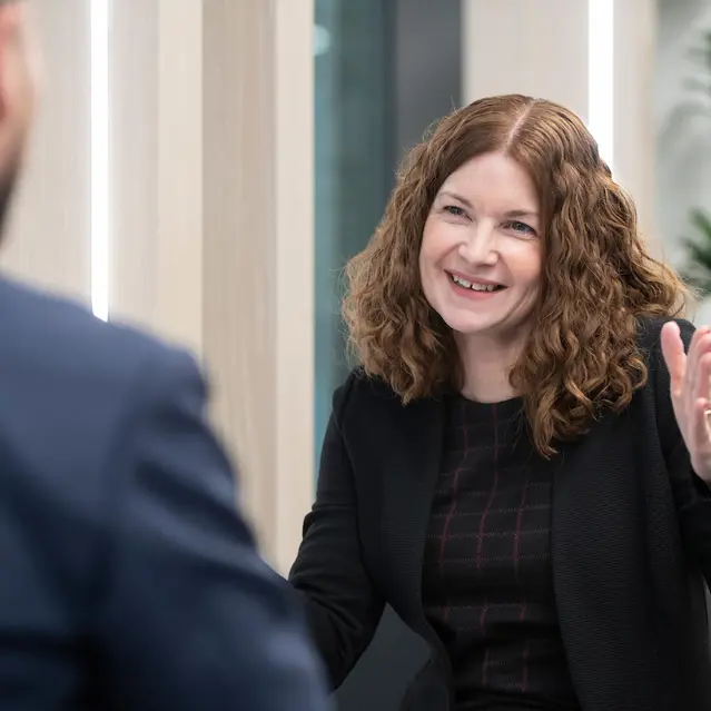 Smiling woman with curly hair gesturing in conversation