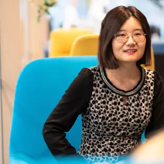 Portrait of smiling woman with glasses in blue chair